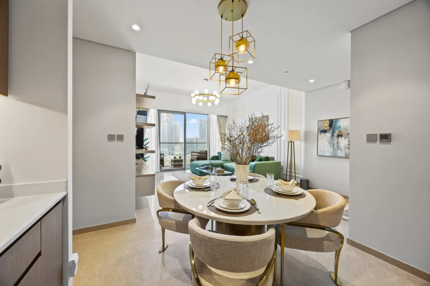 Open-concept dining area with a white round table set for four, beige upholstered chairs, and a city skyline visible through large windows.