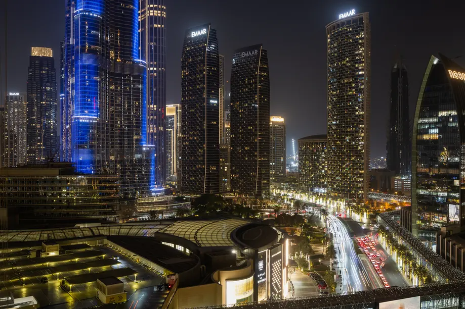 Night city skyline with tall illuminated skyscrapers and a busy street below.
