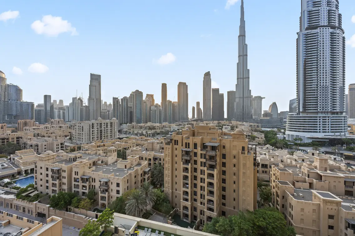 Dubai cityscape with beige apartment buildings in the foreground and the tall skyline including Burj Khalifa start of the distance.