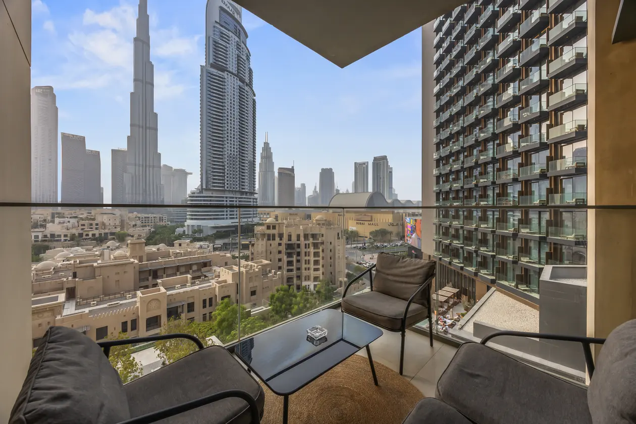 Balcony seating with glass railing overlooking Dubai’s skyline and tall towers.