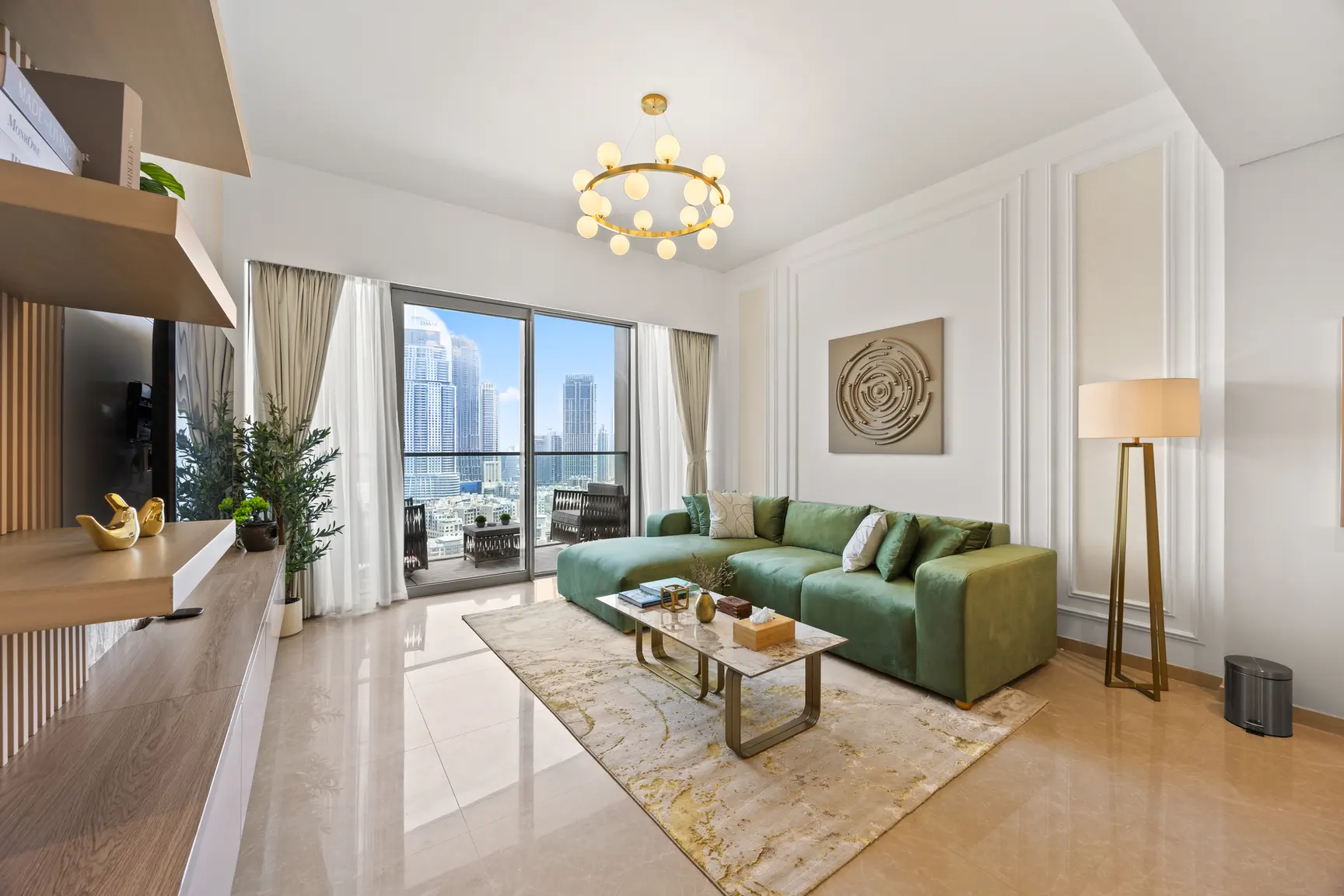 Bright living room with a green sectional sofa, marble coffee table, and a cityscape view through glass doors.