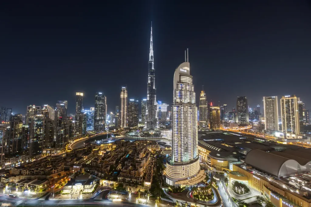 Nighttime aerial view of Dubai's skyline, centered on the Burj Khalifa with surrounding illuminated high-rises and roads.” (informative)