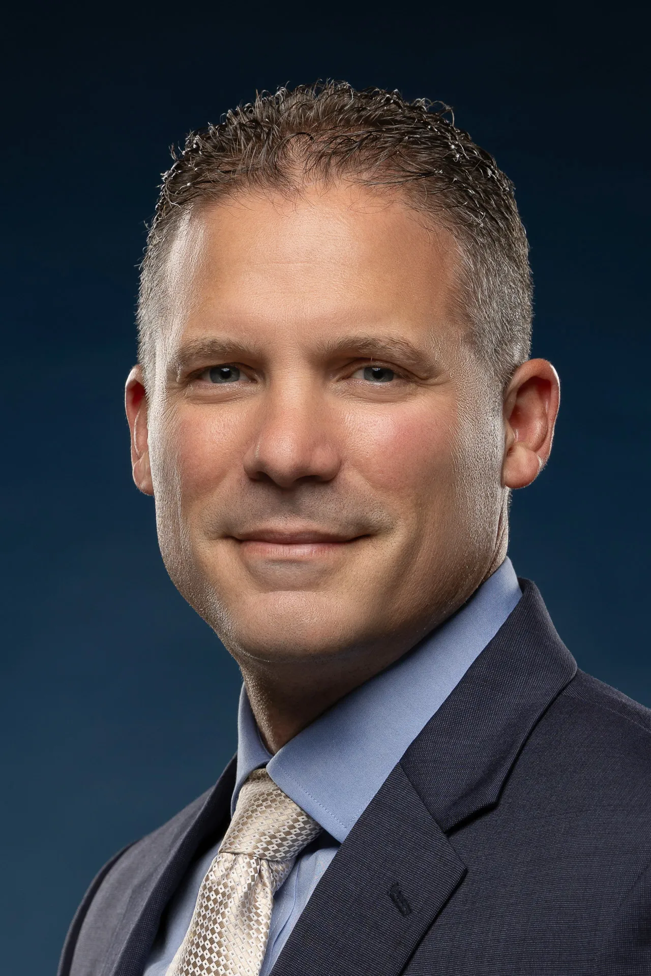 Professional corporate headshot photography Dubai - male executive in navy suit and blue shirt, studio portrait by Masoud Raoufi Photography