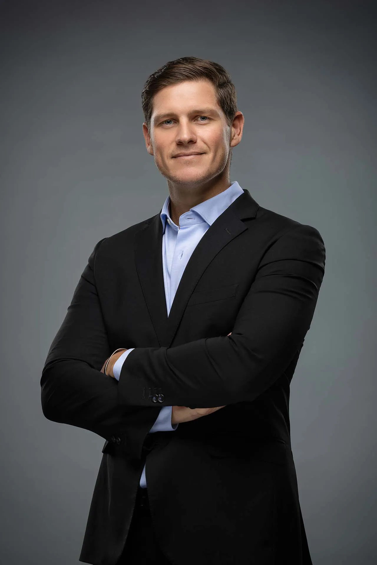 Professional headshot of a man in a black suit with arms crossed at a Business Bay photography studio in Dubai