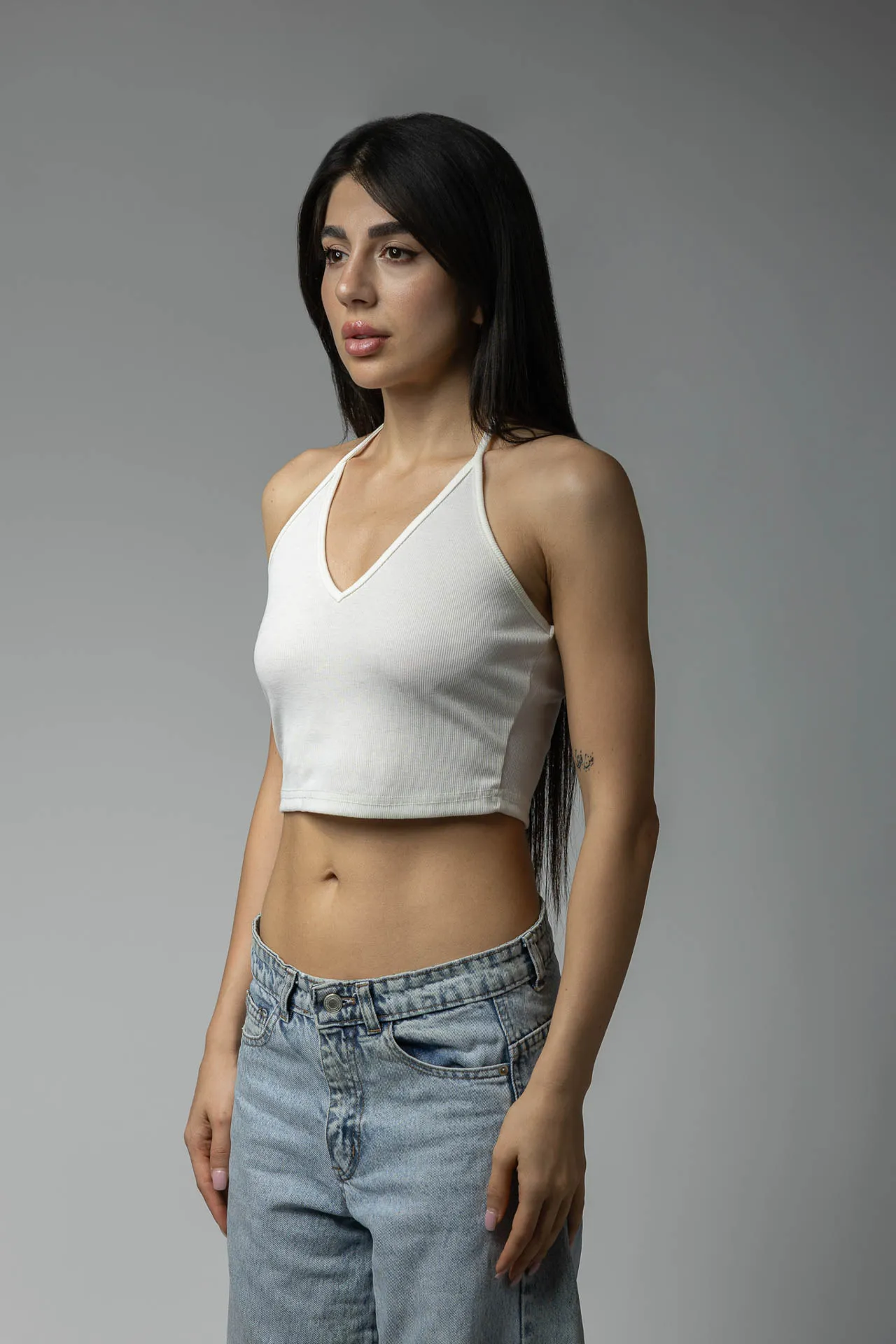 Female model with long dark hair in white halter top and jeans — agency digitals, Dubai modeling portfolio