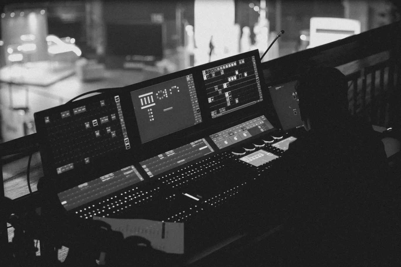 Professional audio mixing console with multiple screens and faders in a dimly lit recording studio