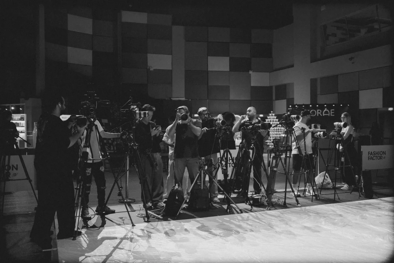 Group of photographers with cameras on tripods in a studio setup, ready to shoot a fashion event without visible models in frame.