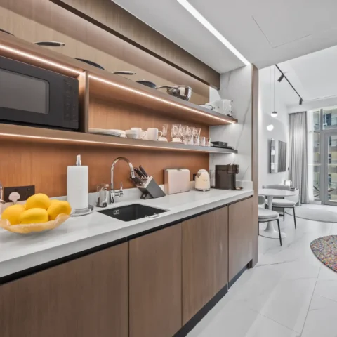 Modern kitchen with warm wood cabinets, white countertop, and microwave on a shelf above the counter.