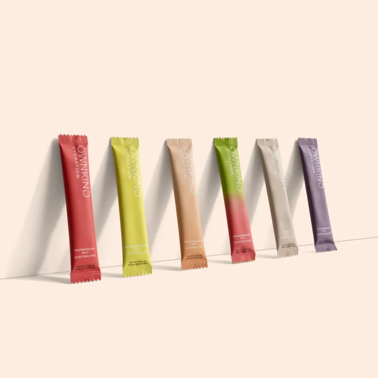 Row of colorful electrolyte supplement sachets angled along a pale beige background.