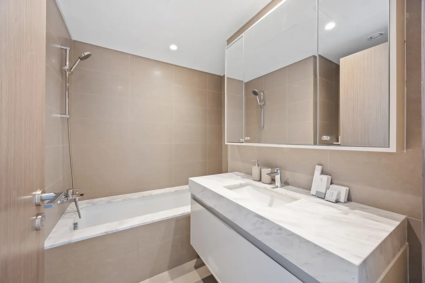 Contemporary bathroom with marble countertop vanity, large mirrored cabinet, beige tile walls, and a wall-mounted shower.