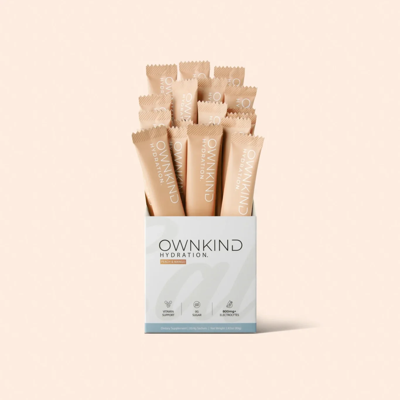 Box of O W N K I N D hydration sachets arranged upright with peachy-beige packaging; peach & mango flavor label visible on a pale background.
