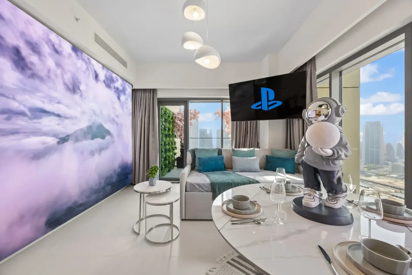 Modern living room with a purple cloud mural, large windows showing a city view, teal cushions, and a silver astronaut statue on the table.