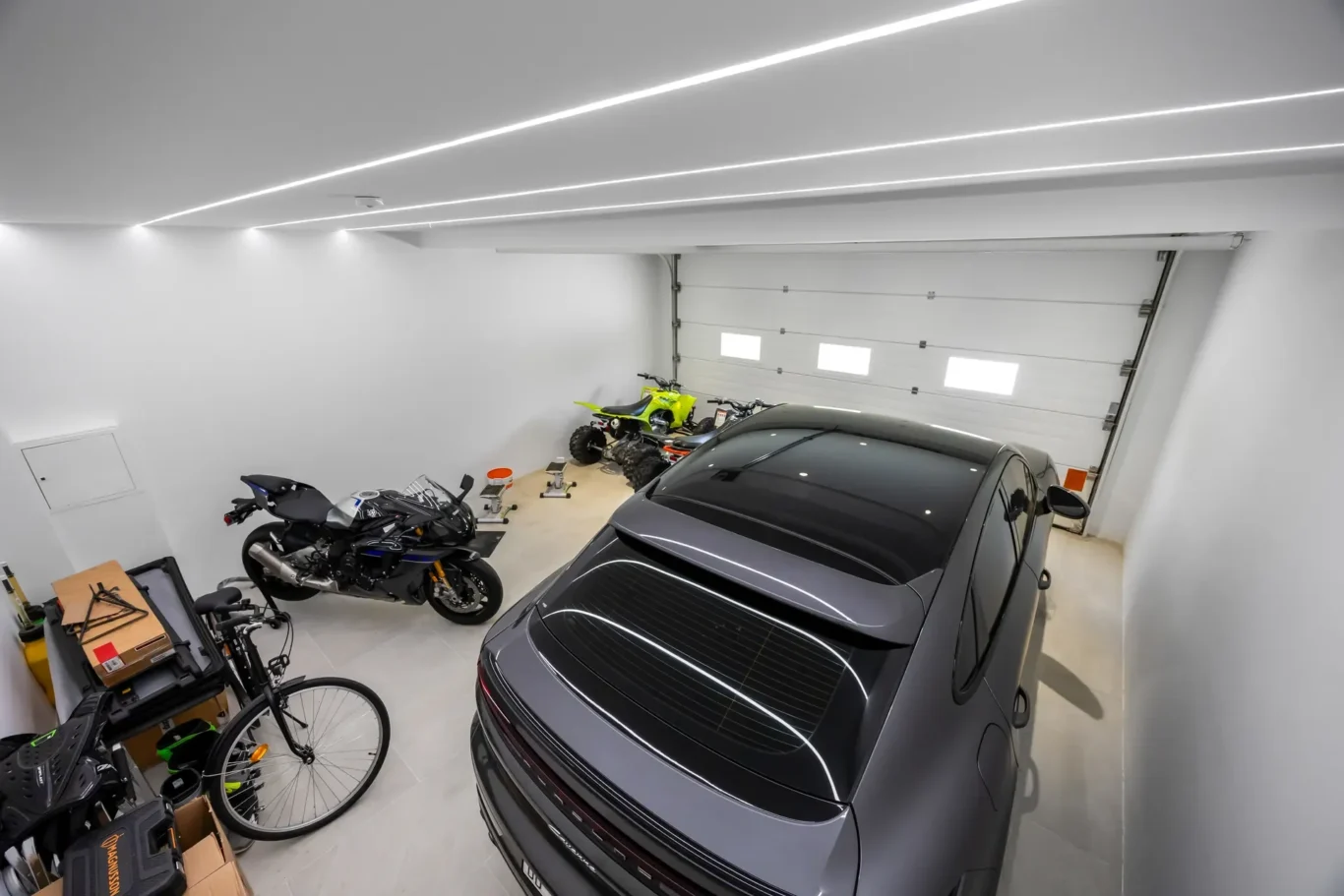 Bright garage with a gray SUV foreground, and a motorcycle and bicycle along the left wall.