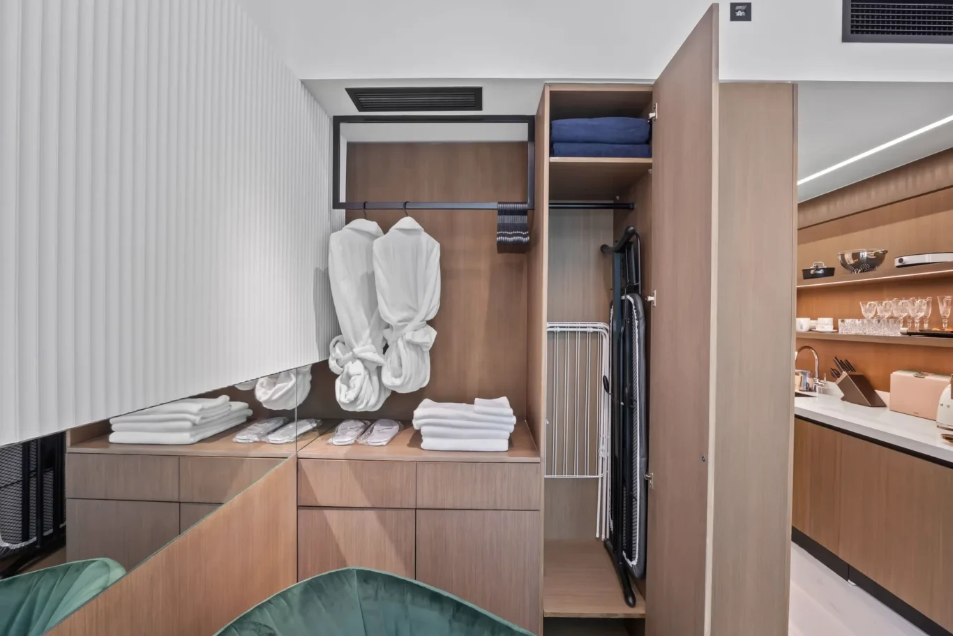 Walk-in closet with white robes on a hanging rack, folded towels, and open shelves in a wood cabinet