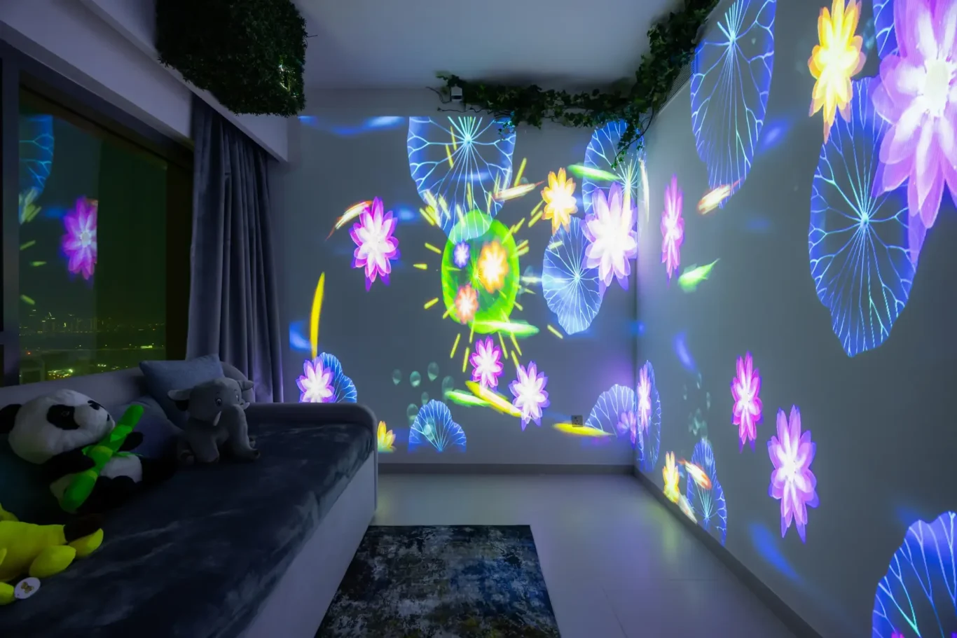 Child's living room with neon projection of colorful flowers and circular patterns on walls, plush toys on a sofa, nighttime city lights outside window.