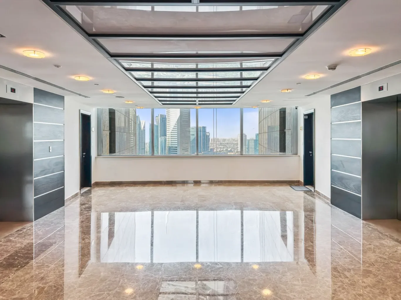 Modern elevator lobby with two side-by-side elevators, polished marble floor, and large windows showing a city skyline outside.