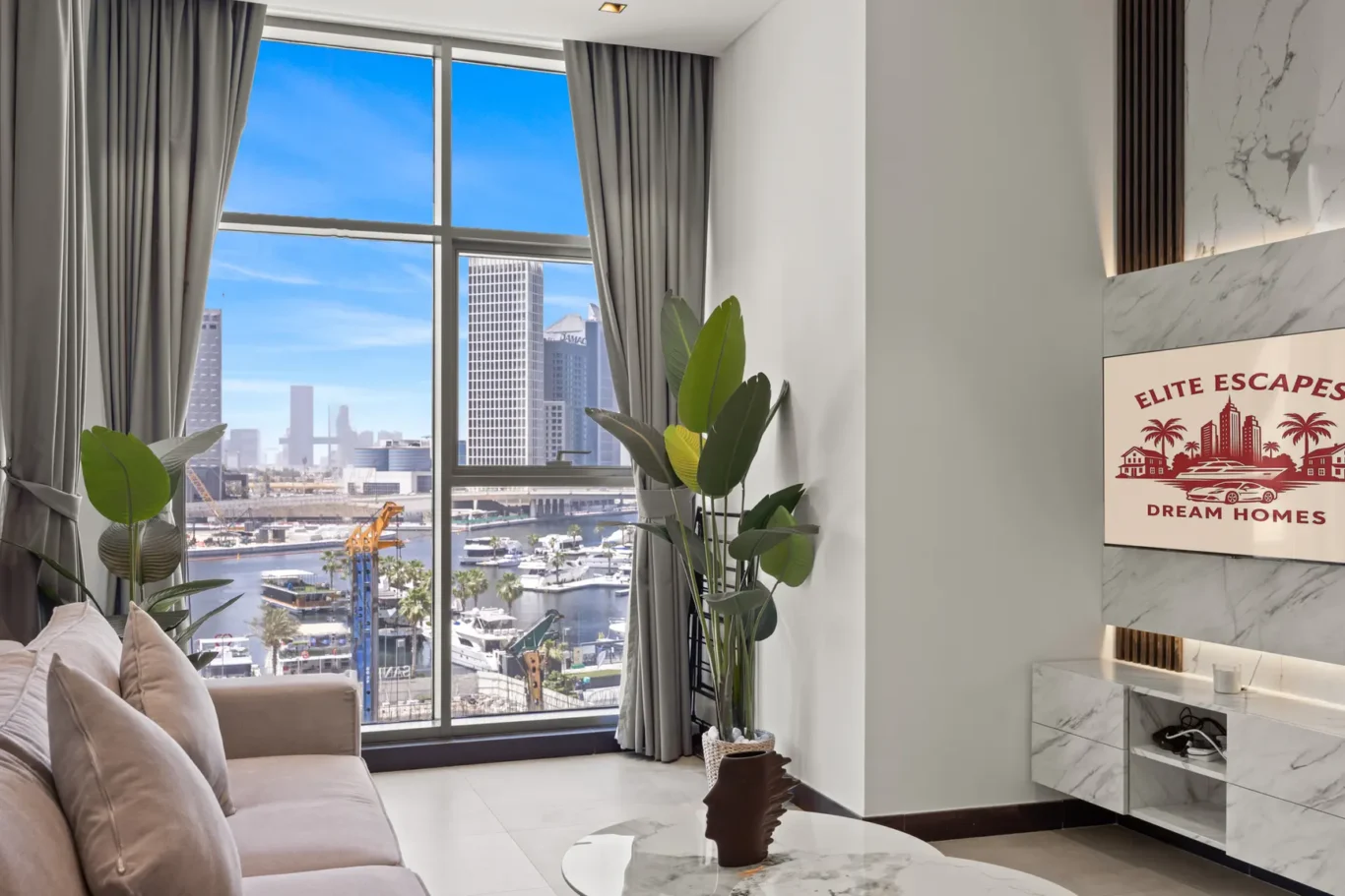 Living room with a large window showing a marina and city skyline, gray drapes, and potted plants in the corner.