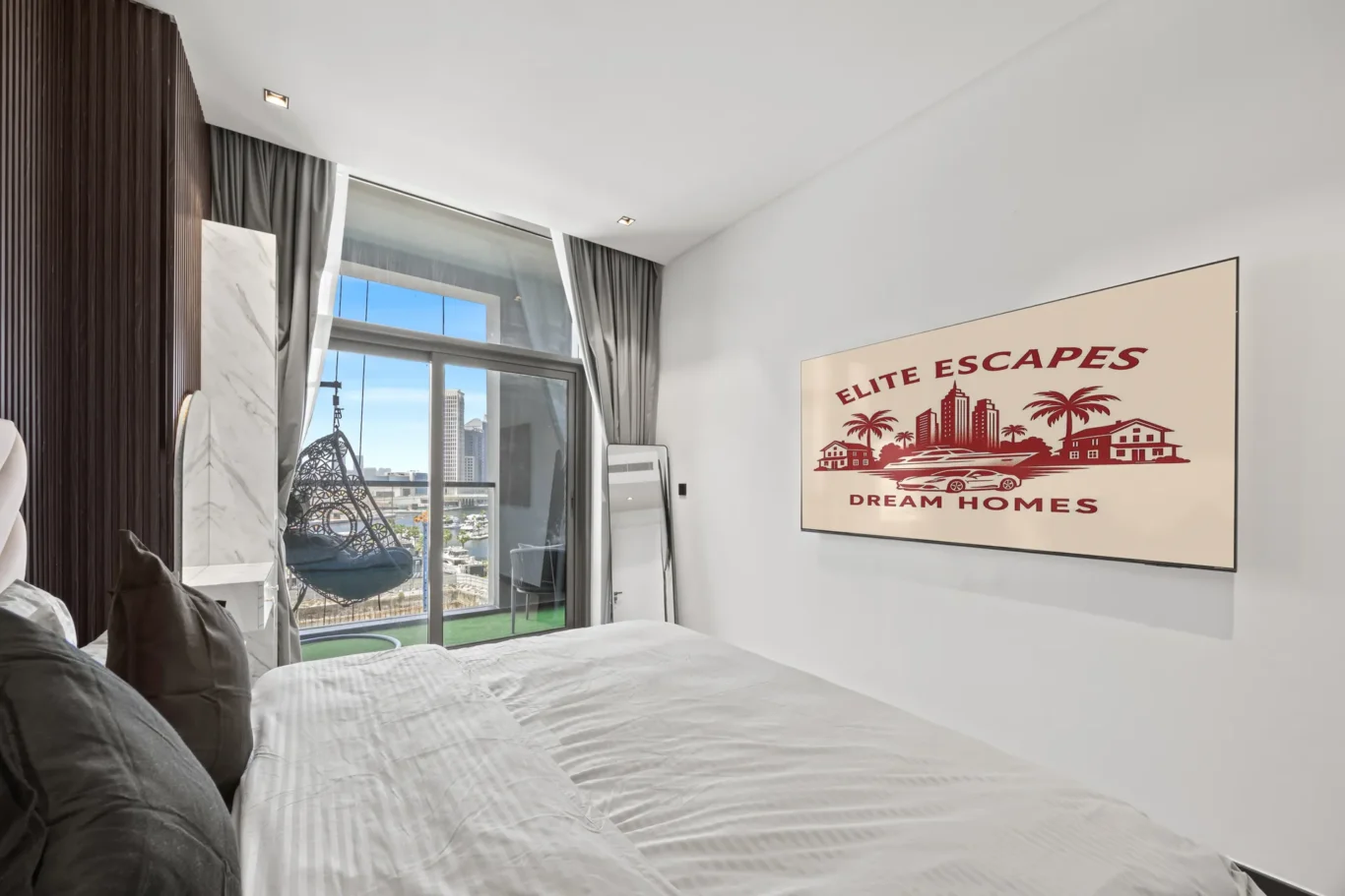 Modern bedroom with a large 'Elite Escapes Dream Homes' mural, white bedding, and a glass door to a balcony over the city.