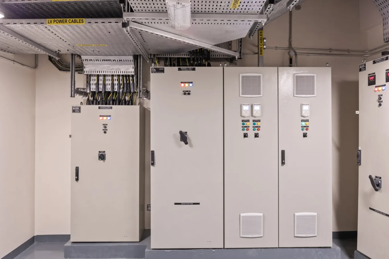 Electrical switchgear in a service room with labeled LV power cables and BMS cables