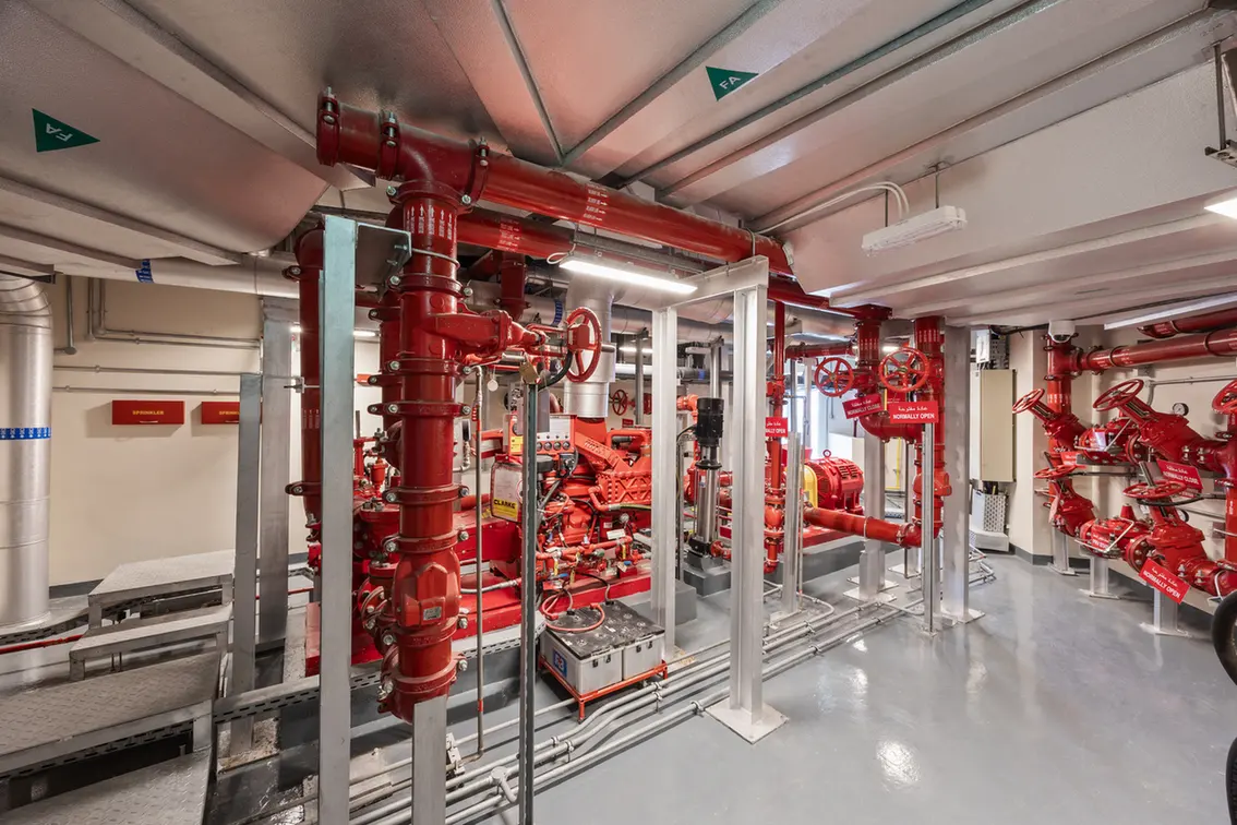 Fire pump room with red pumps, large valves, and interconnected piping for fire suppression.
