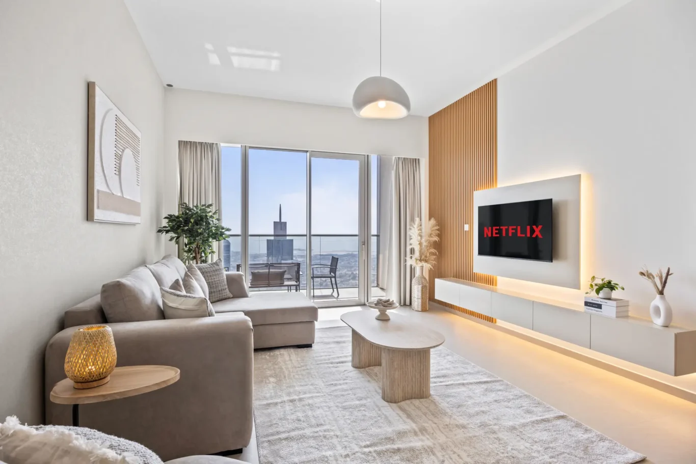 Spacious modern living room with a beige sectional facing a wall-mounted Netflix TV and warm wood slat paneling.