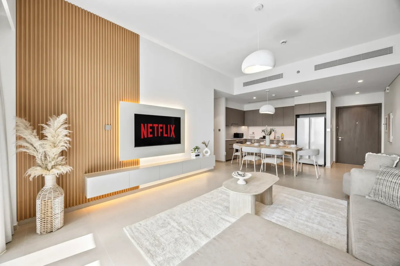 Living room with a wall-mounted Netflix screen on a white panel beside a wood slat accent wall.