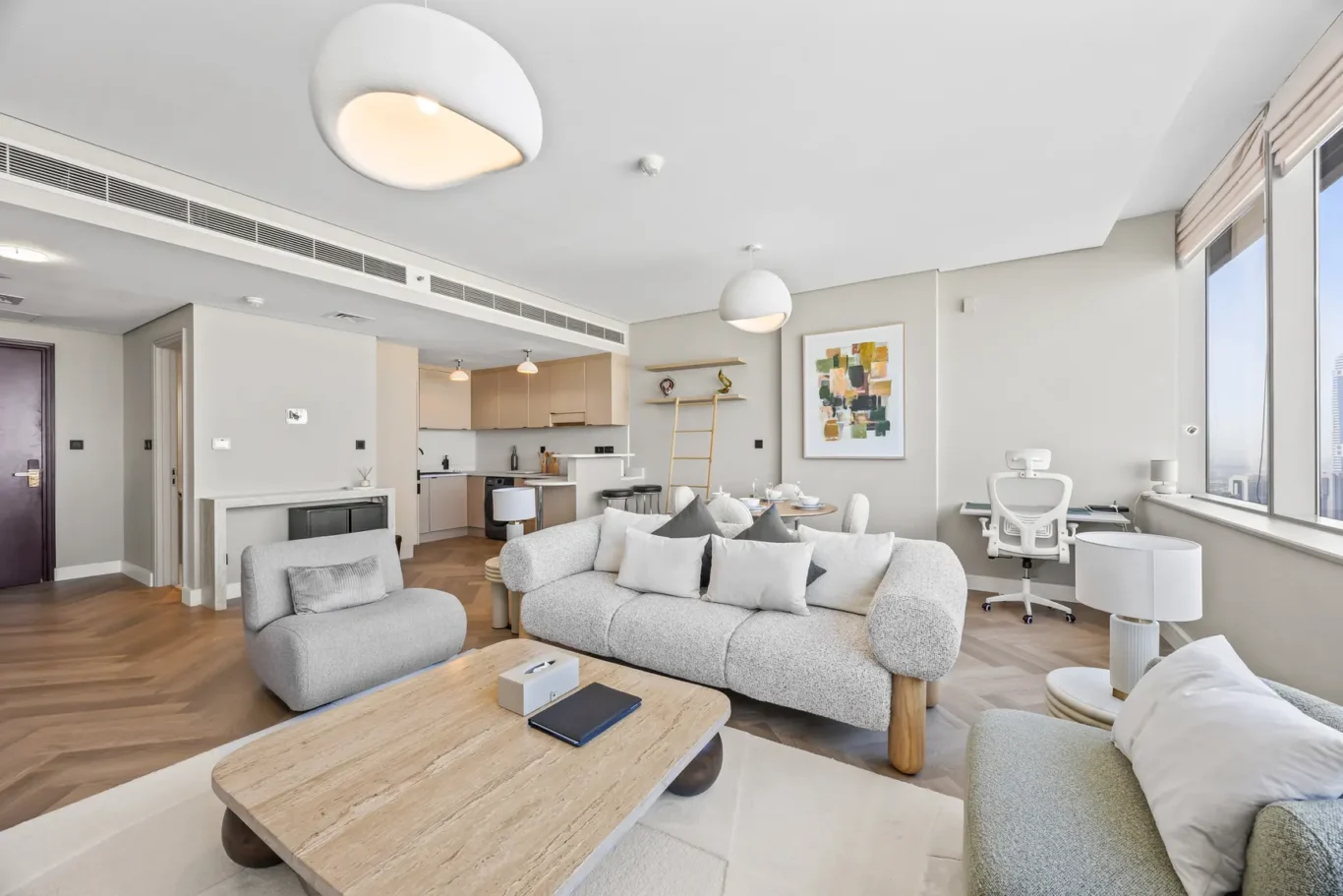Open-plan living room with gray sofas, a wooden coffee table, and a white kitchen in the background.
