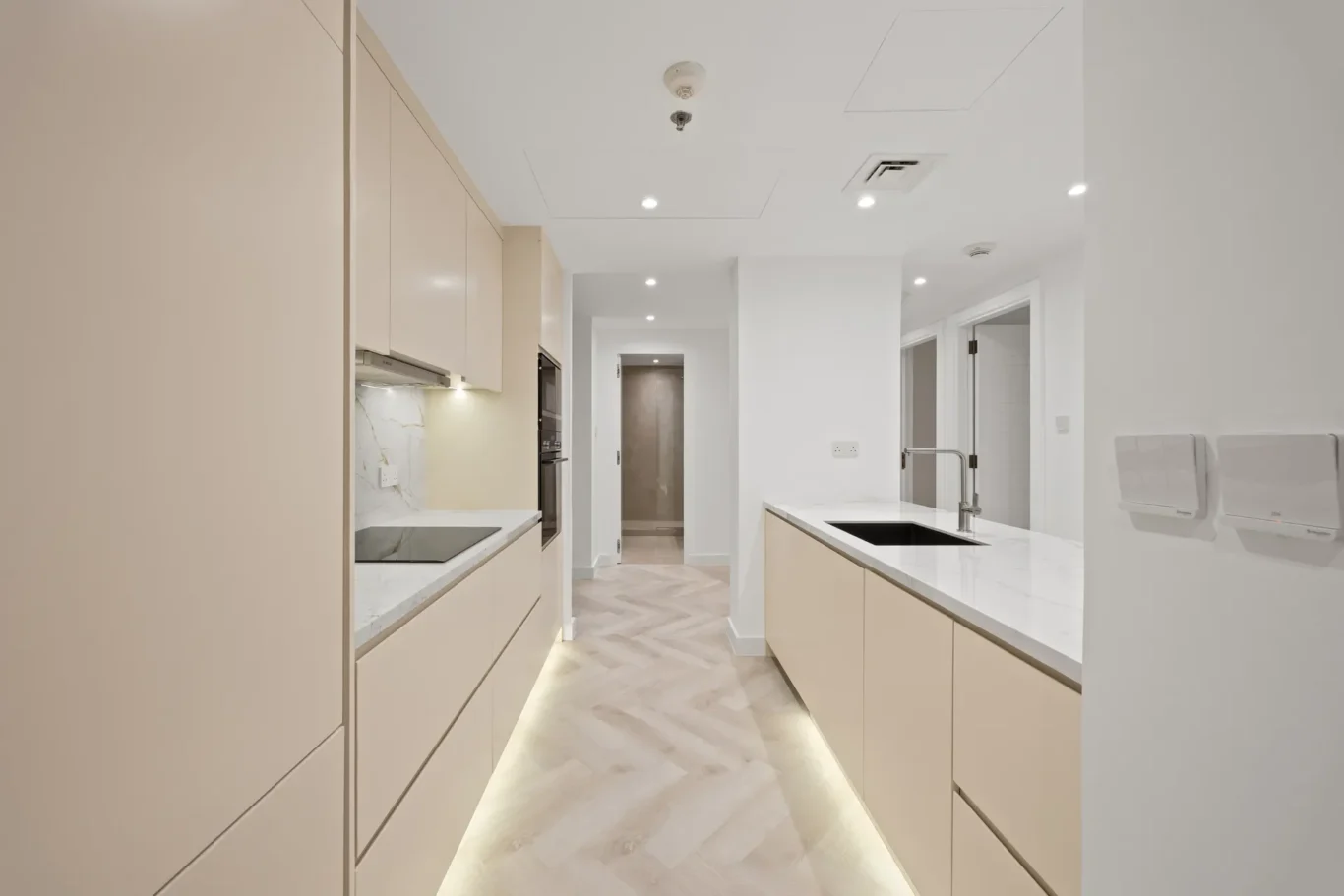Bright, modern kitchen with beige cabinets, marble countertops, and an island with a sink and chrome faucet in a sunlit space.