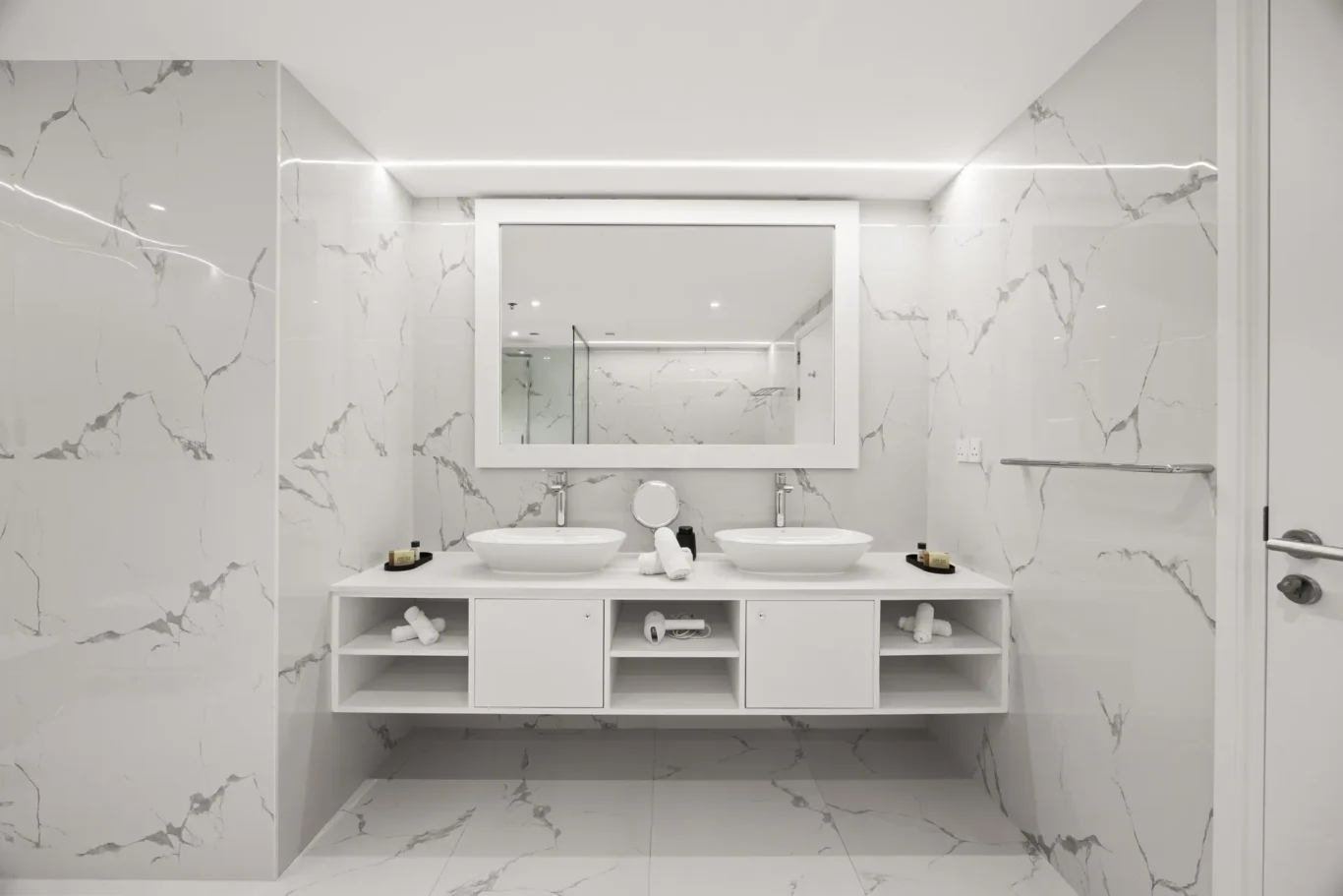 Modern marble bathroom with double vessel sinks, large framed mirror, and open-shelf vanity.