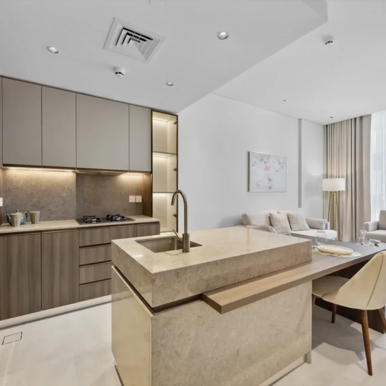 Open-plan kitchen and living area in a modern apartment with a marble island, gray cabinets, and a balcony view.