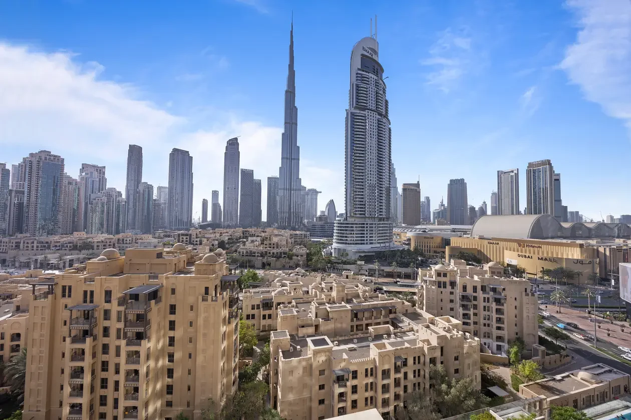 Dubai cityscape with the Burj Khalifa towering above surrounding skyscrapers and beige residential buildings in the foreground on a clear day.