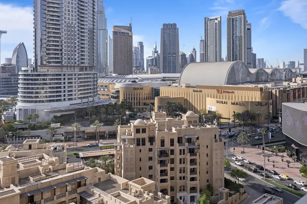 Dubai skyline with tall glass skyscrapers and the Dubai Mall in the foreground.