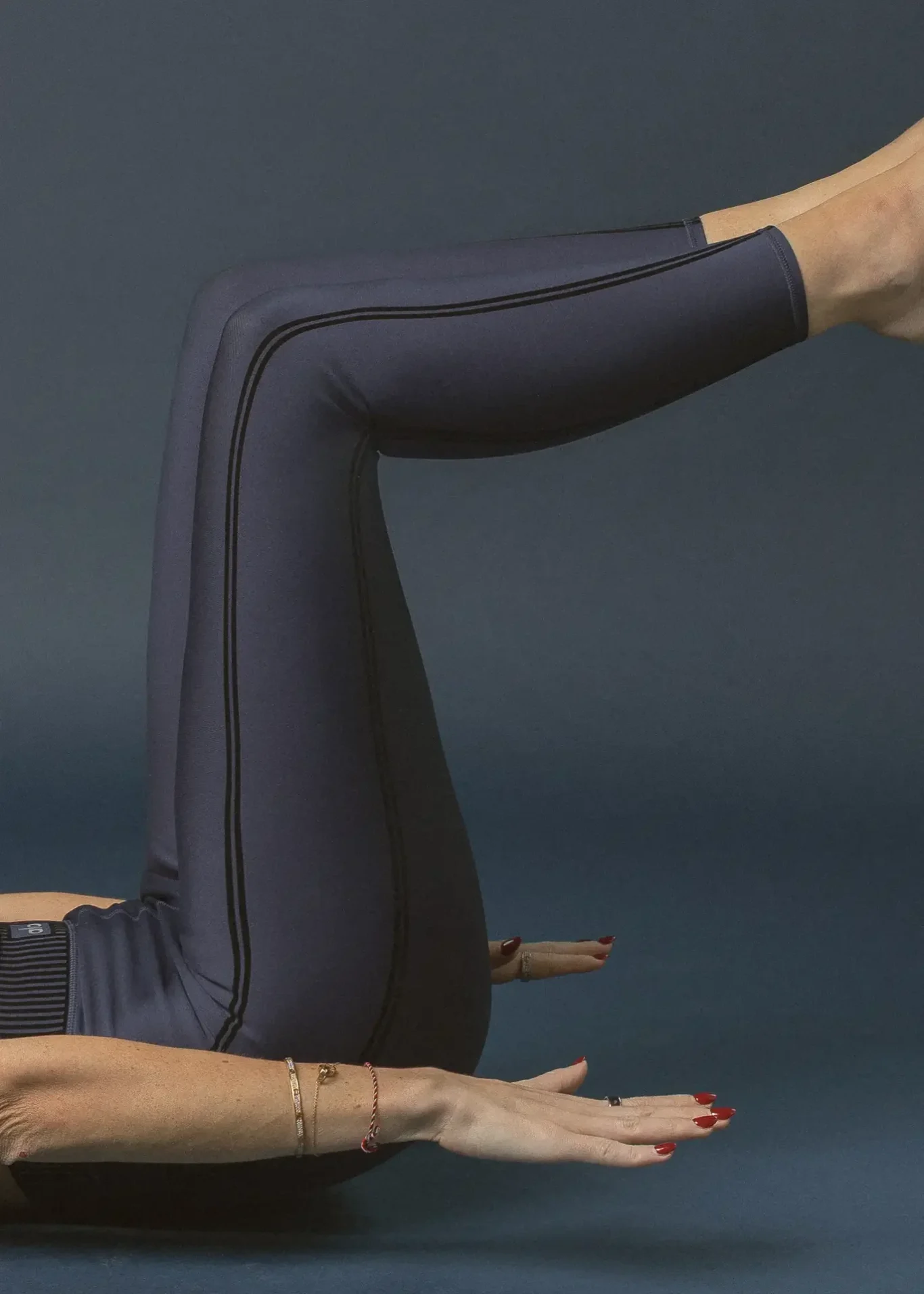 Person in navy athletic wear performing a balance yoga pose with leg raised and arms extended forward against a dark backdrop.