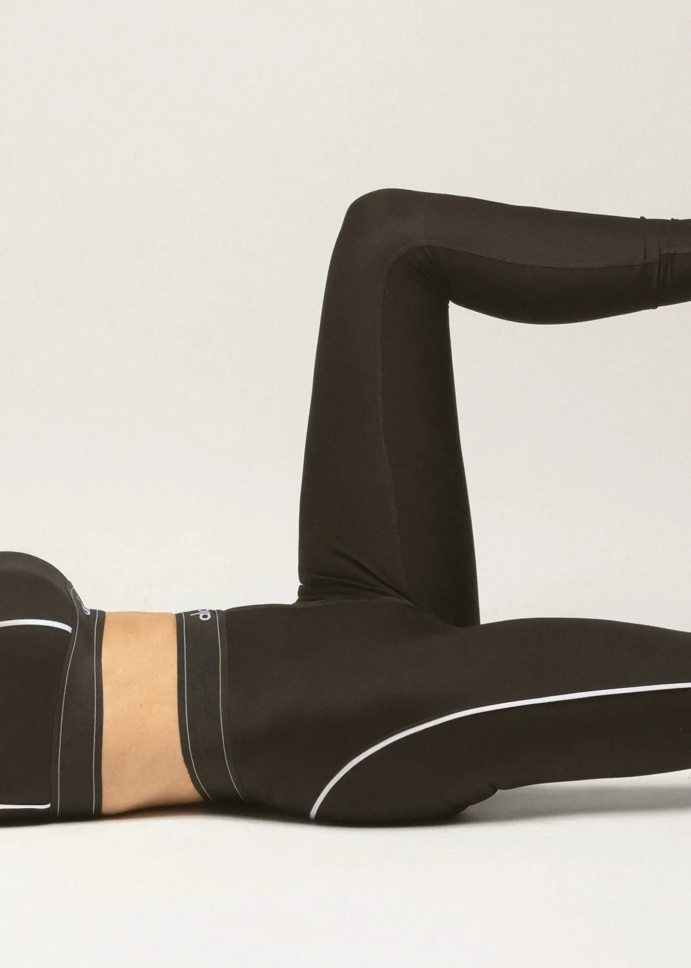 Person in black workout clothing performing a leg raise exercise.