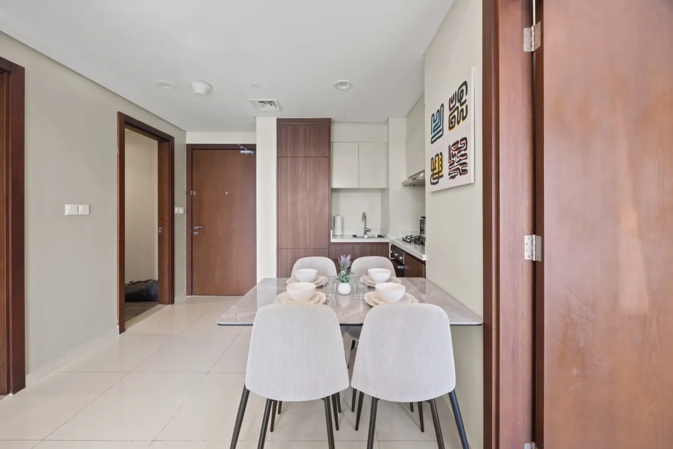 Dining table set for six in a bright open-plan kitchen with wooden cabinets in the background