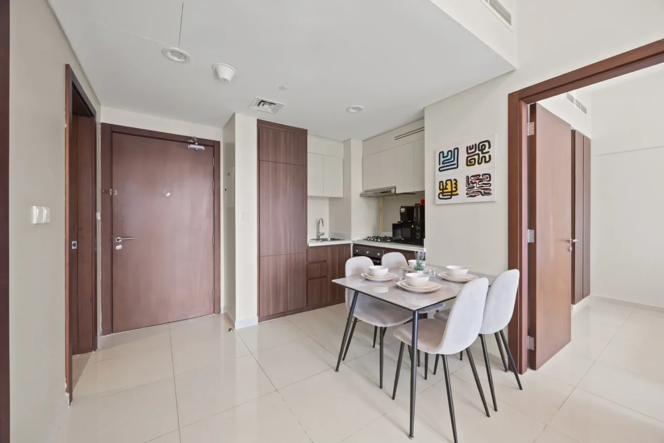 Open-plan kitchen and dining area with a wooden cabinet wall, white countertops, and a table set for six bowls and plates.