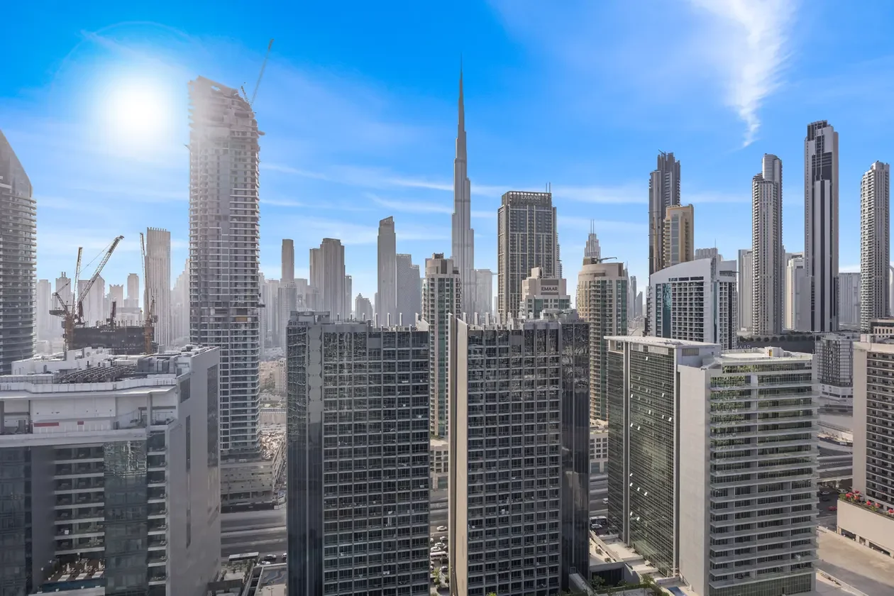 City skyline with many high-rise glass buildings under a bright blue sky at midday.