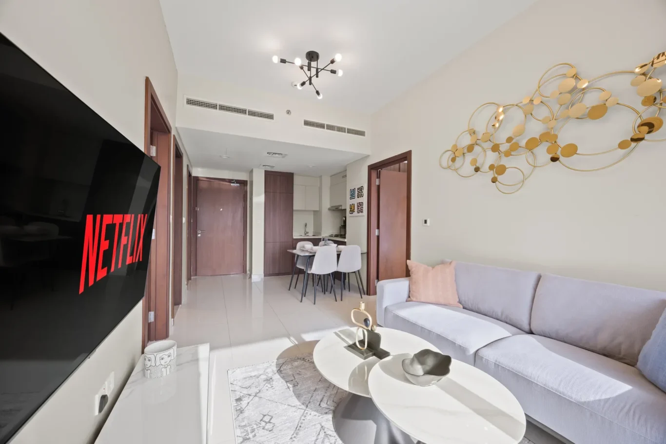 Living room with a gray sectional sofa, marble coffee tables, and a large TV showing Netflix.