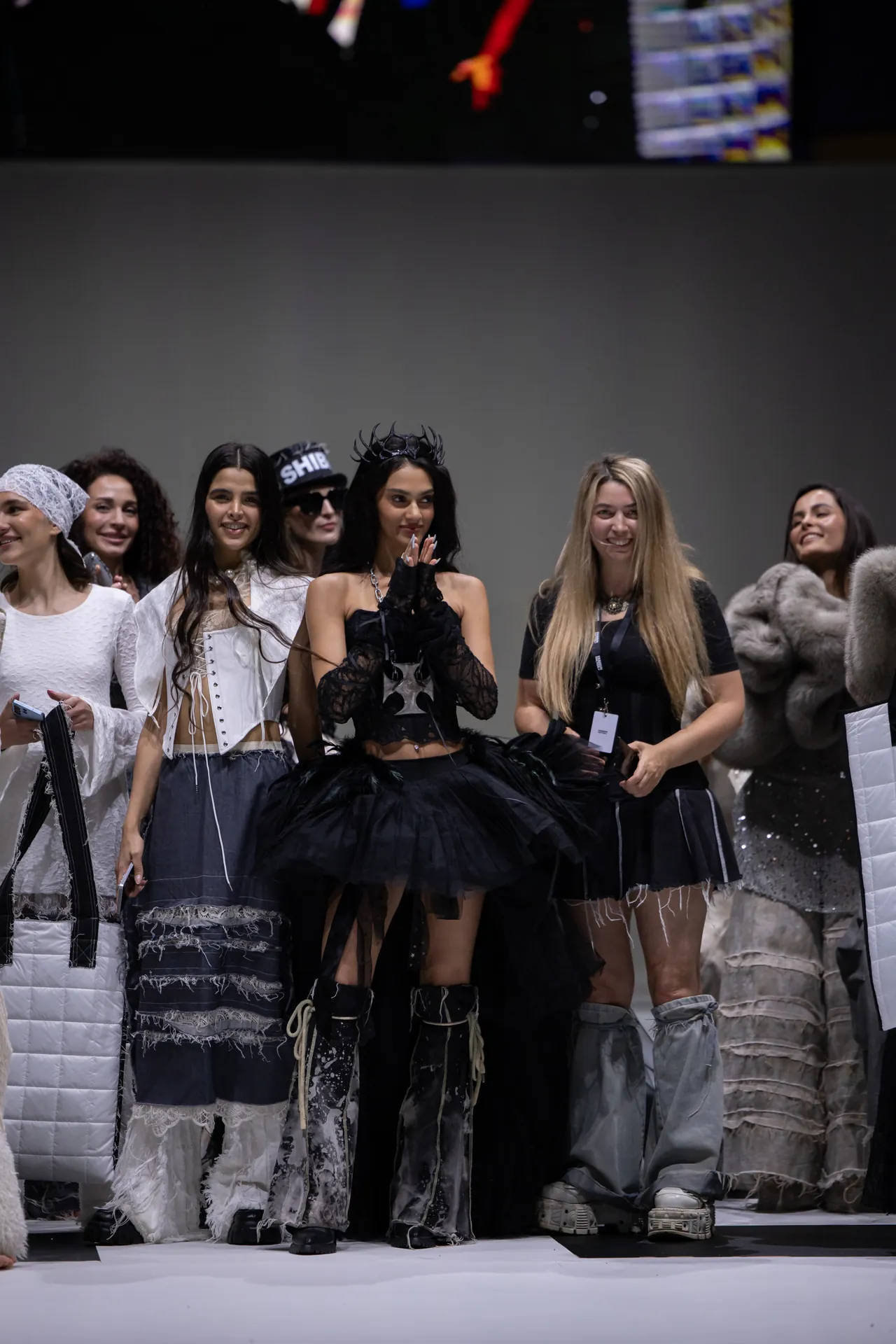 Group of models on a runway posing in dramatic black-and-white haute couture outfits during a fashion show edge-to-edge lineup