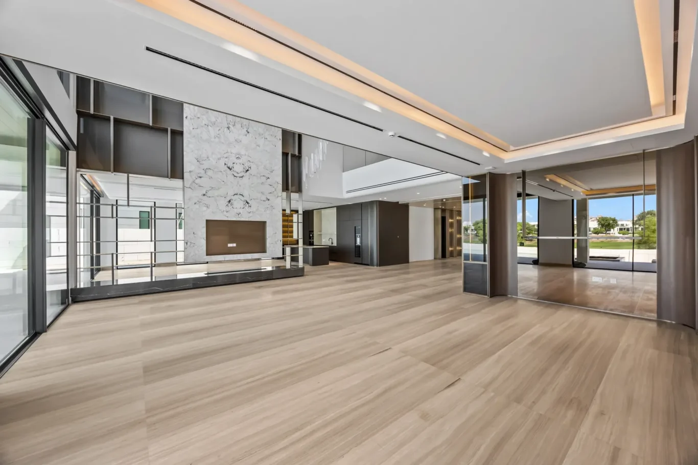 Spacious modern lobby with wood floors, glass walls, and a marble feature wall centerpiece.