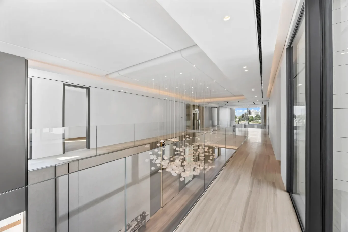 Bright modern office lobby with glass balustrade, white walls, and a view of outdoors through the far windows.