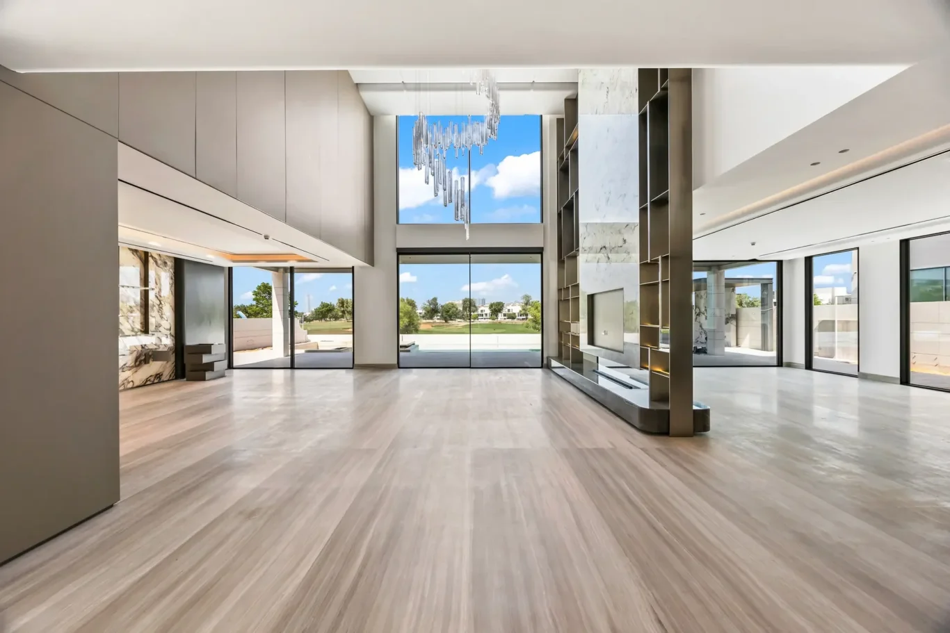 Spacious modern lobby with floor-to-ceiling windows, marble accents, and a sculptural crystal chandelier.