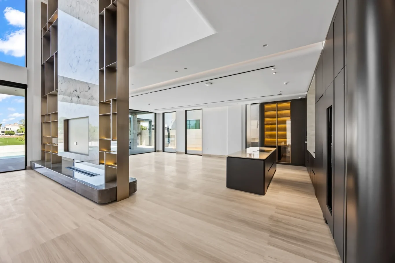 Contemporary lobby with a marble feature wall, glass entry doors, and a dark reception island bathed in natural light from the left window.