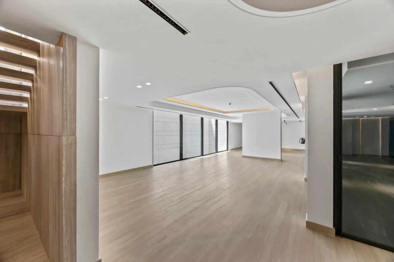 Modern, bright lobby with light wood flooring, white walls, and large glass doors along the back wall.