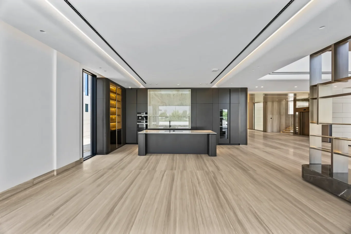 Modern open-concept kitchen with dark cabinets, island, and light wood flooring in a showroom setting