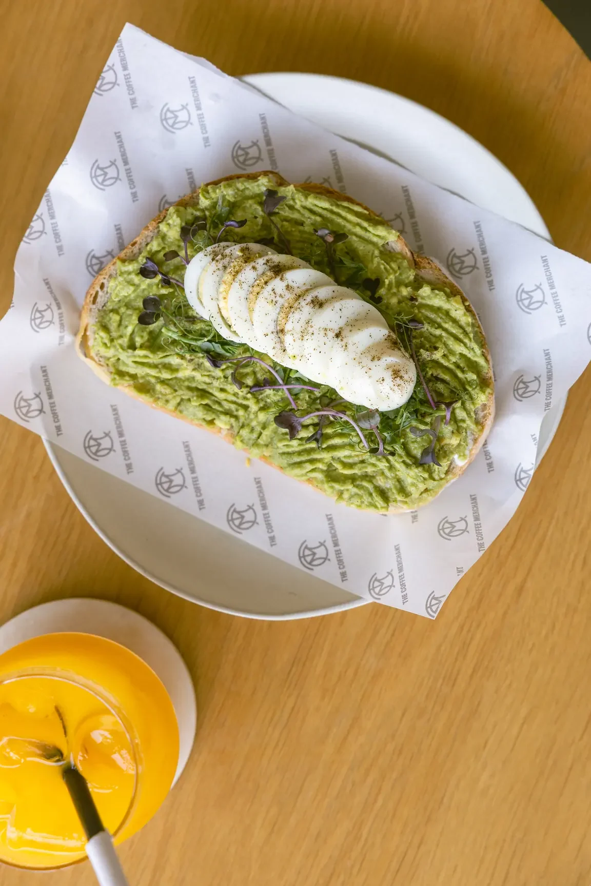 Open-faced avocado toast topped with sliced hard-boiled egg and microgreens on a toasted bread slice