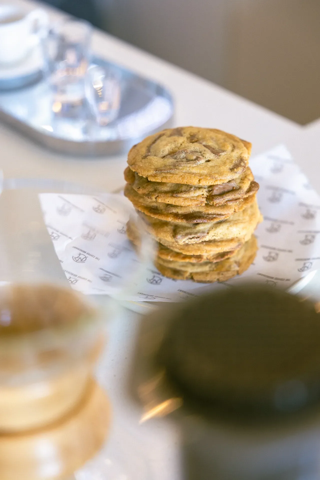 Stack of golden brown cookies stacked on parchment paper in a bright cafe setting.