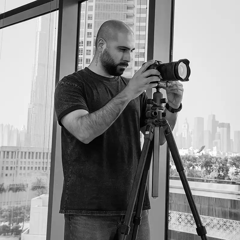 Airbnb photographer in Dubai shooting a holiday home interior on a tripod, with the Downtown Dubai skyline and Burj Khalifa through the windows