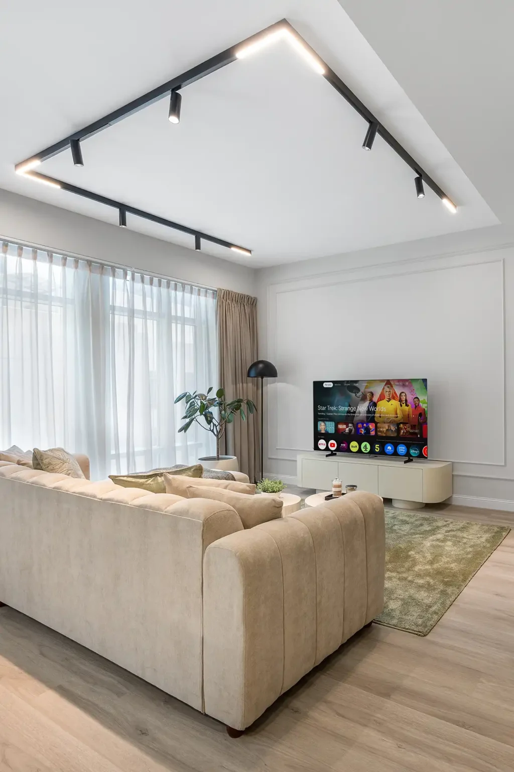 Airbnb photography Dubai - bright living room with beige sofa, smart TV and sheer curtains in a Dubai holiday home