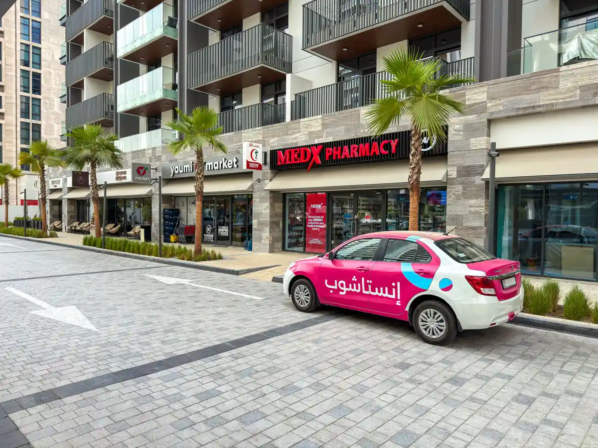 Retail street at Crest Grande, Sobha Hartland: supermarket, pharmacy, salon and cafe within the building, daylight
